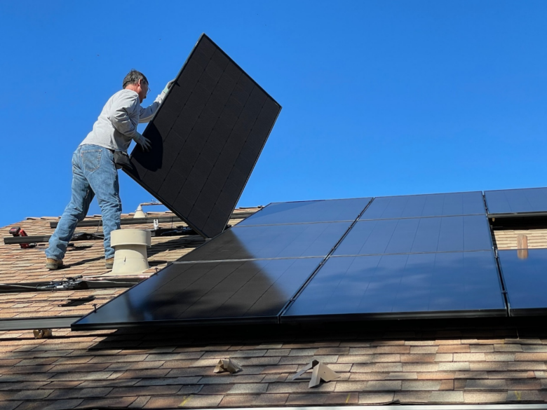 A person installing solar panels, one of the best sustainable home features